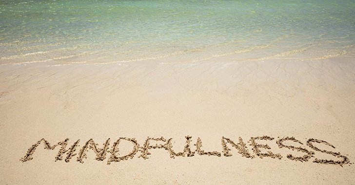 Mindfulness written in sand on a beach