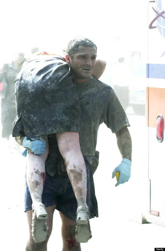 United States Secret Service Agent Thomas Armas, carries an injured woman to an ambulance after Tower One of World Trade center collapsed. (Photo By: Thomas Monaster/NY Daily News via Getty Images)