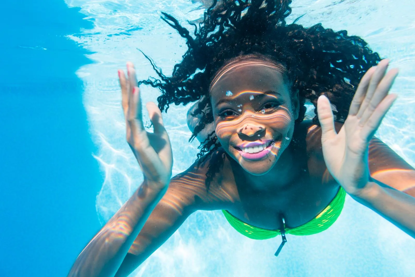 An attractive Black woman diving in swimming pool at vacation