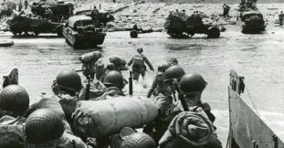 American troops landing at Omaha Beach, June 6, 1944. The presence of tracked vehicles and DUKWs (โDucksโ) on the beach and the organized columns of men heading inland indicate that this photo was taken several hours after the initial infantry assault.